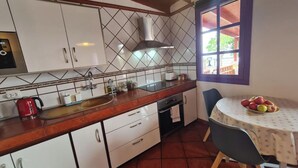 A kitchen with white cabinets, a red kettle, a sink, and a window with a view of greenery. - Los Cerrajones: spectacular views from the cliff (Agulo)