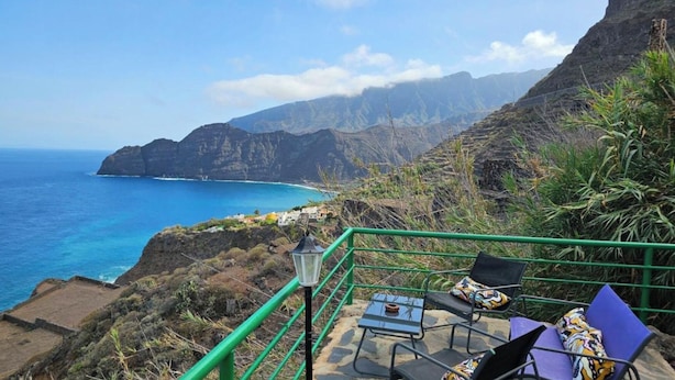 A terrace with a view of the ocean and mountains, a table, chairs, and a lamp. - Los Cerrajones: spectacular views from the cliff (Agulo)