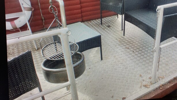 A covered outdoor seating area with chairs and a table, a red wall, and a white railing. - Small houseboat ideal for fishing.   Contact us +49 177 5927586 (Lychen)
