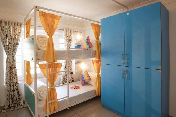 A bunk bed with yellow curtains, a blue wardrobe, and a sun shining through the window. - goSTOPS Srinagar (Srinagar)