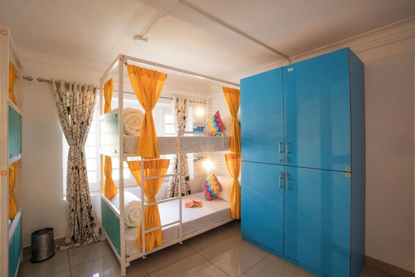 A bunk bed with yellow curtains, a blue wardrobe, and a small trash bin. - goSTOPS Srinagar (Srinagar)