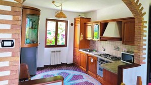 A kitchen with wooden cabinets, a microwave, and a gas stove. - LA VILLETTA (Piemonte)