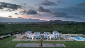 Un grand complexe hôtelier moderne doté de plusieurs villas, d’une piscine et d’un jardin paysager bien entretenu.