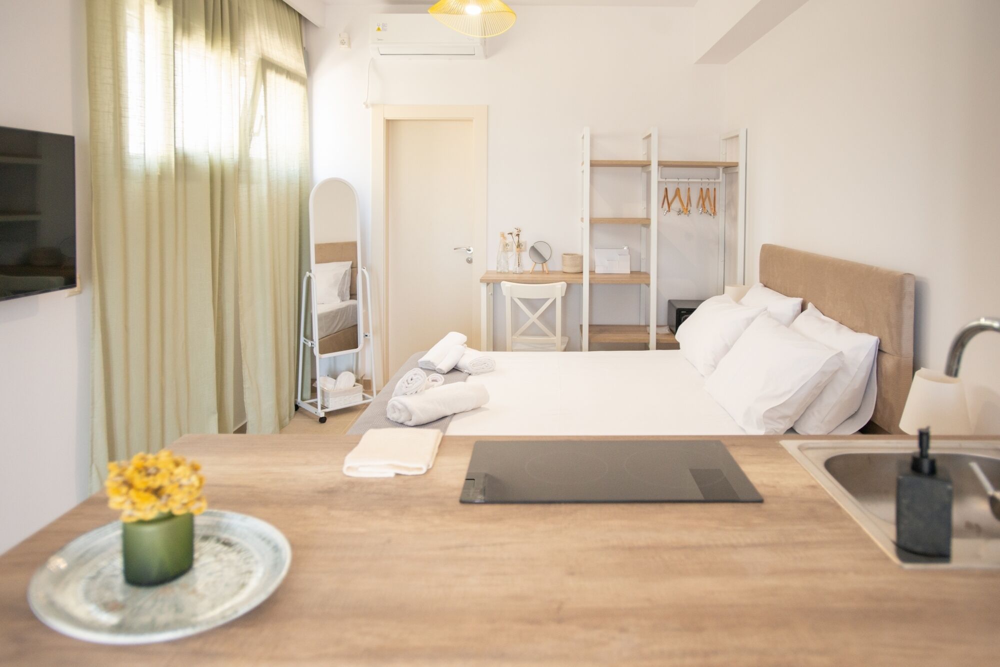 Habitació d'hotel amb llit, taulell de nit, escriptori, cadira, armari i un bany petit.