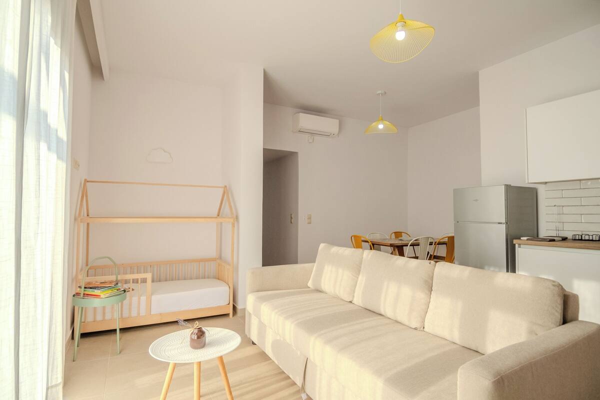 A modern, well-lit living room with a sofa, a small table, and a bunk bed.