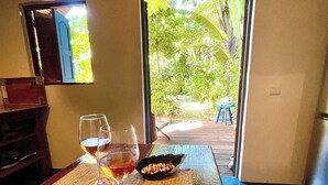 A dining table with a woven placemat, two wine glasses, and a bowl of nuts. - Comfortable Malagasy bungalow on private beach (Analanjirofo)