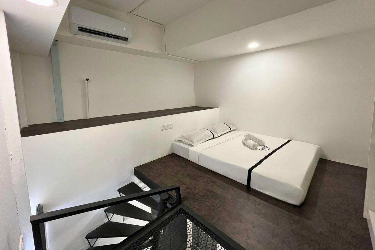 Une chambre d’hôtel avec un lit, une petite table et un escalier.