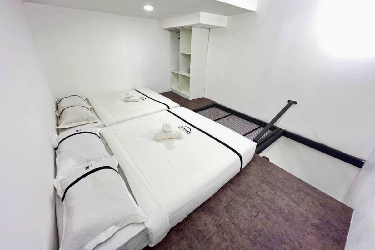 Une chambre d’hôtel avec deux lits, un petit coin salon et un escalier.