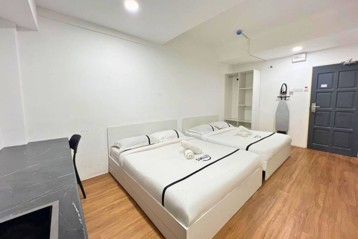 Une chambre d’hôtel avec deux lits, un bureau, une chaise, une armoire et un miroir.