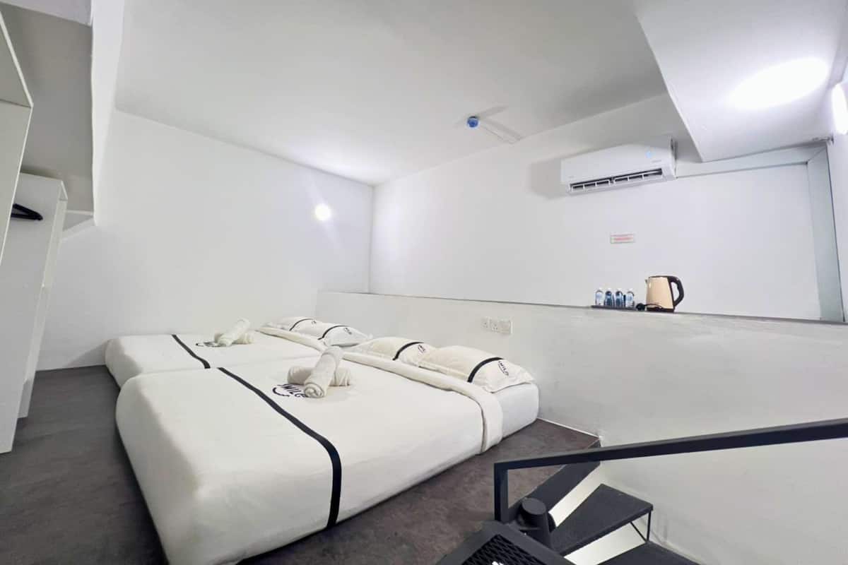 Une chambre d’hôtel avec un grand lit, une petite table avec une bouilloire et un appareil de climatisation fixé au mur.