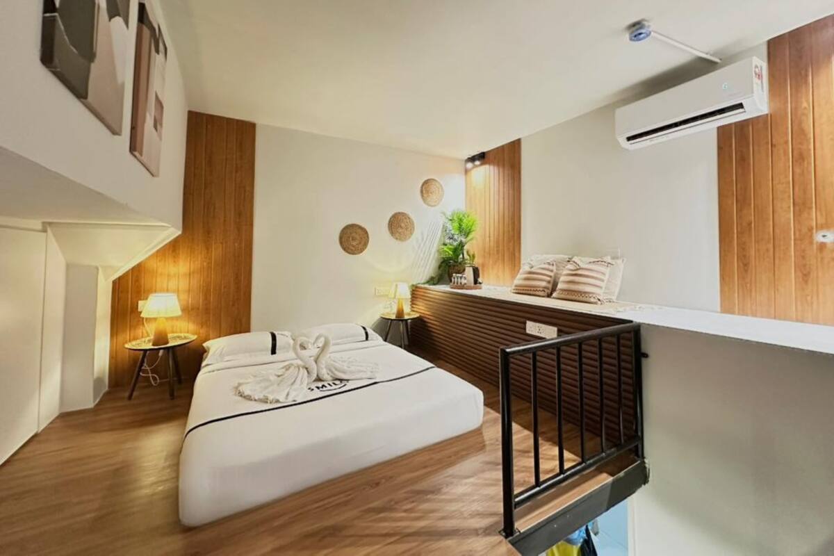 Une chambre d’hôtel comprenant un lit, une table de chevet, une lampe, des éléments de décoration murale et un appareil de climatisation.