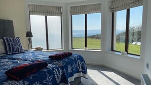 Ein Schlafzimmer mit zwei Betten, großen Fenstern und Blick ins Freie.