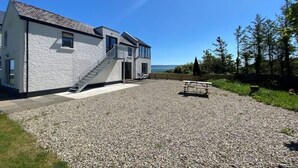 Ein zweistöckiges Haus mit einem Schotterweg und einem Picknicktisch.