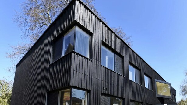 A modern two-story building with a black exterior, large windows, and a visible entrance. - Raymont Hall (London)