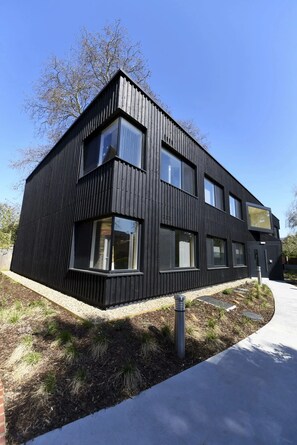 A modern two-story building with a black exterior, large windows, and a visible entrance. - Raymont Hall (London)