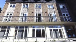 A multi-story building with a brick facade, large windows, and balconies. - Raymont Hall (London)