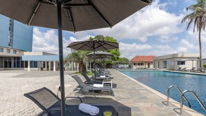 A poolside area with lounge chairs, umbrellas, and a pool.