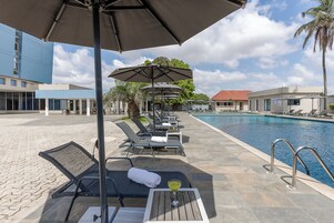 Una piscina al aire libre, sombrillas, tumbonas