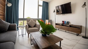 A modern living room with a sofa, armchair, coffee table, and a TV mounted on the wall.