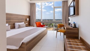 A hotel room with a large bed, a desk, a chair, and a TV.
