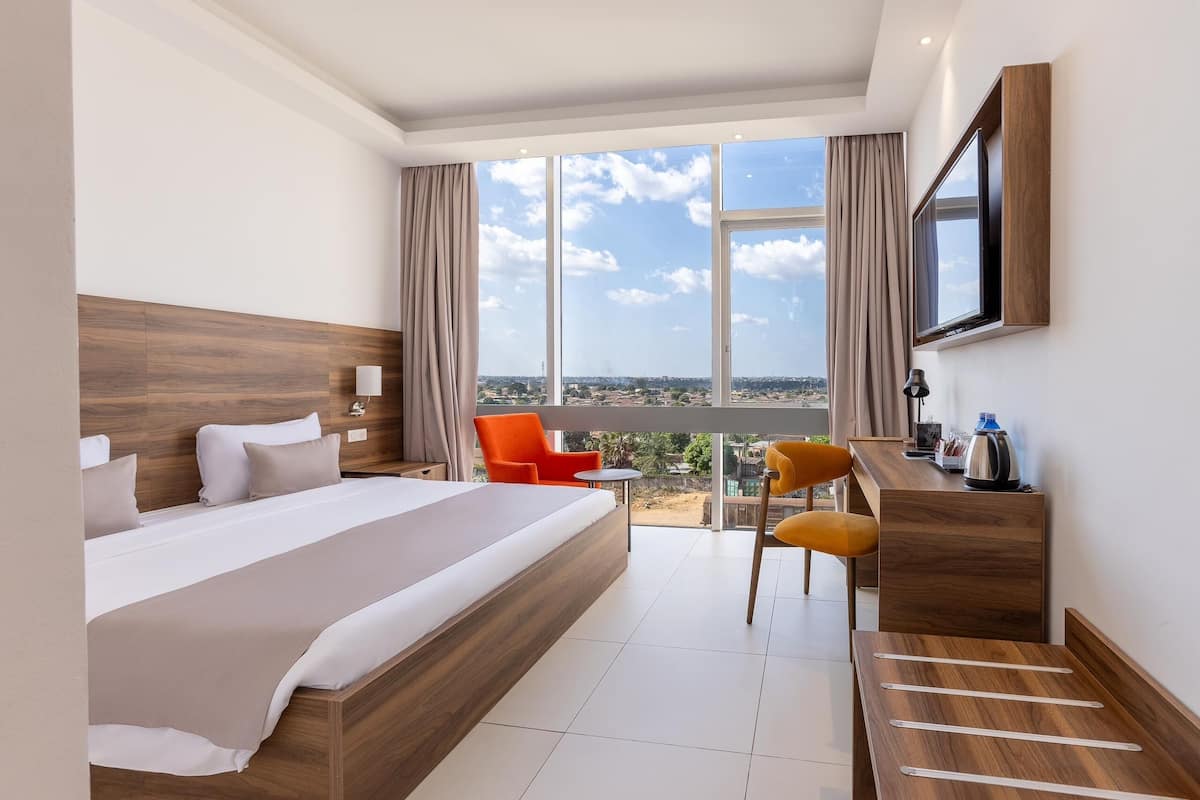 A hotel room with a large bed, a desk, a chair, and a TV.