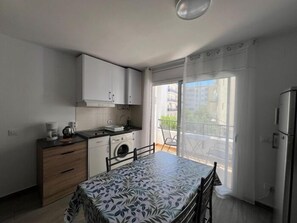 A small, modern kitchen with a dining area, a washing machine, and a view of the outside.