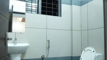A small, compact bathroom with a toilet, sink, and shower.