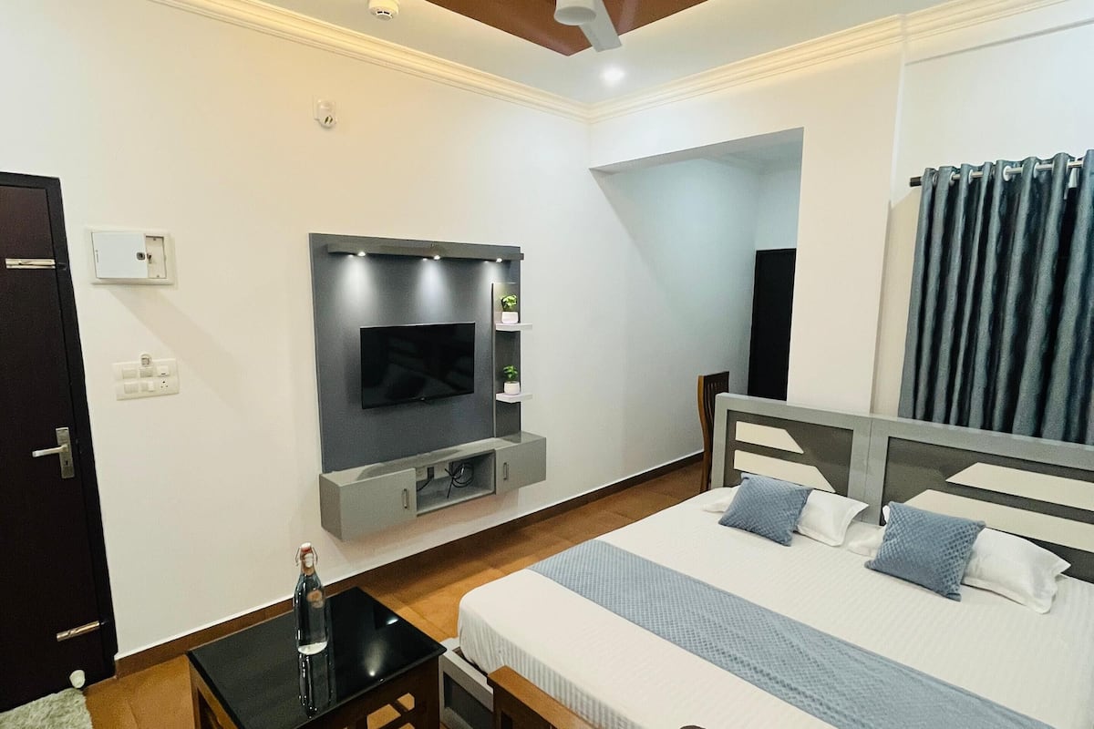 Een hotelkamer met een bed, een televisie, een bureau en een plafondventilator.