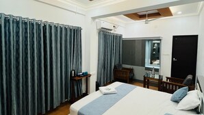Ett modernt hotellrum med en stor säng, ett skrivbord, en stol och en takfläkt.