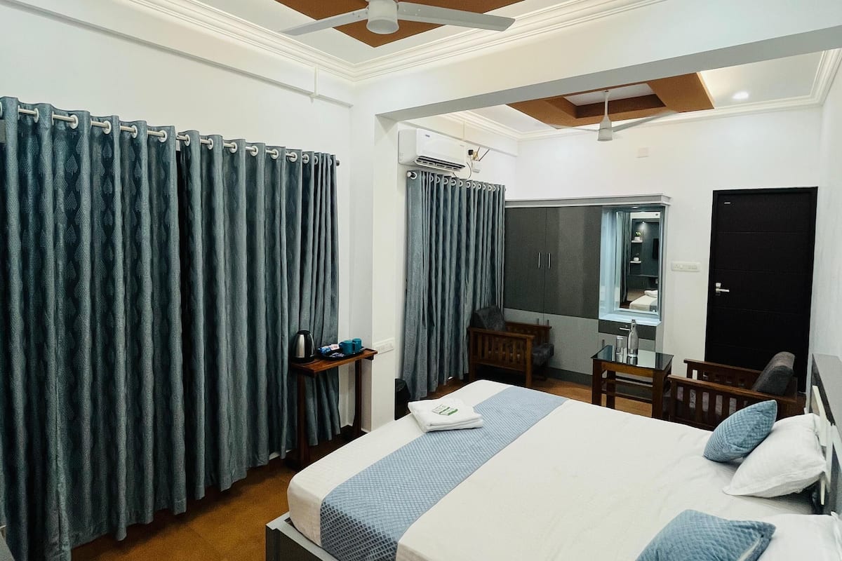 Een moderne hotelkamer met een groot bed, een bureau, een stoel en een plafondventilator.