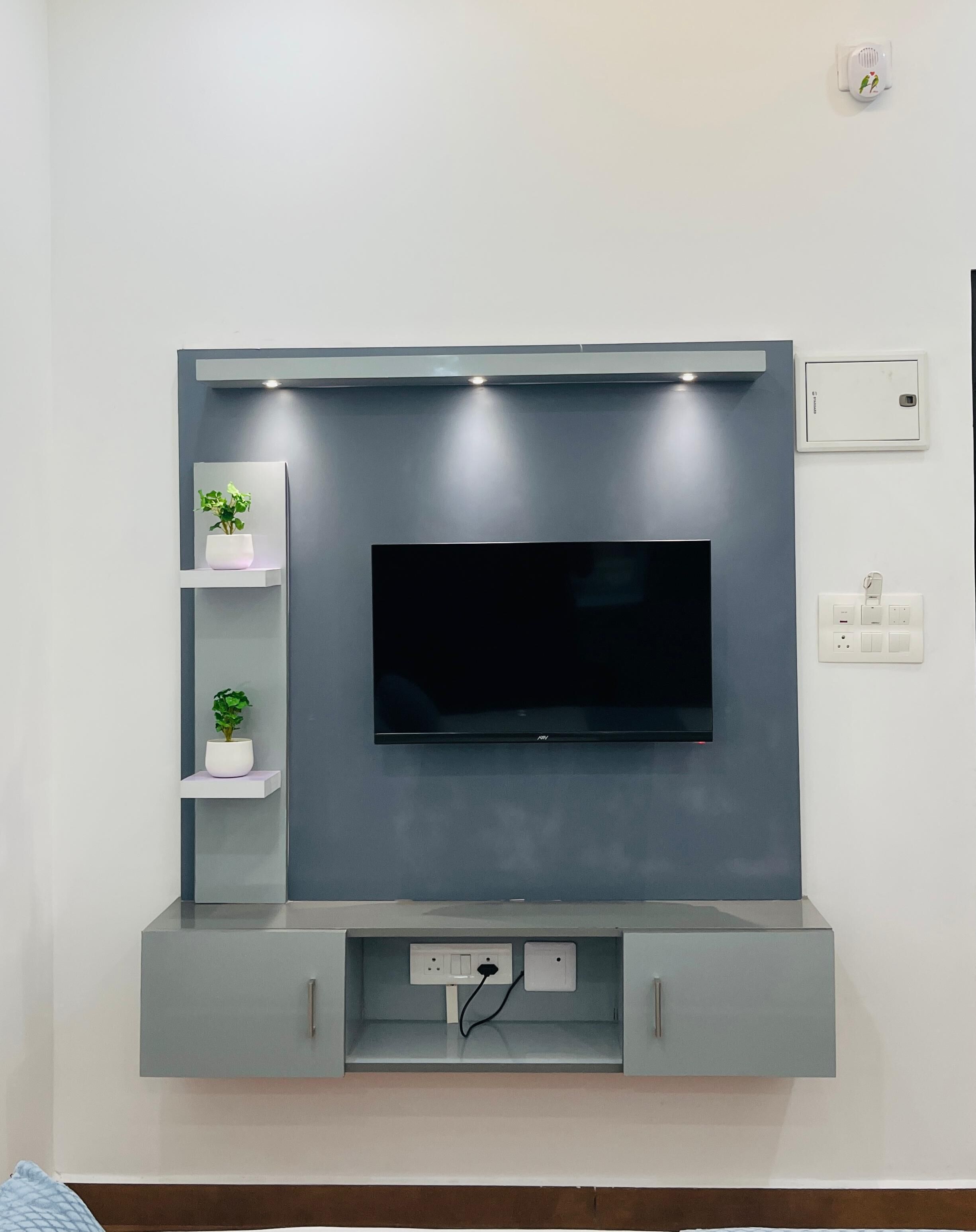 A modern entertainment unit with a flat-screen TV, built-in shelves, and integrated lighting.