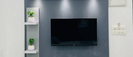 A modern entertainment unit with a flat-screen TV, built-in shelves, and integrated lighting.