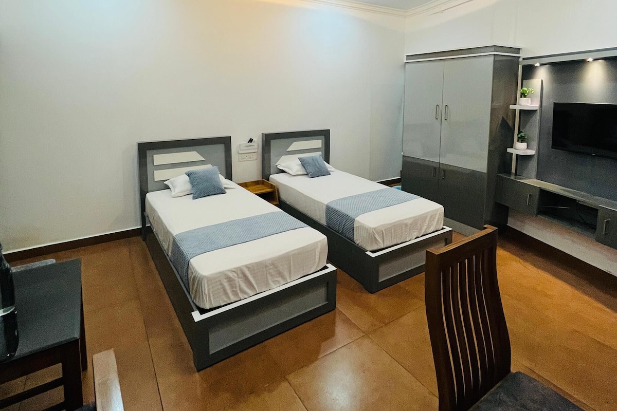 Een hotelkamer met twee bedden, een bureau, een stoel, een kledingkast en een televisie.
