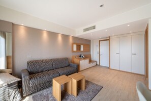 Una camera d'albergo moderna con divano, un piccolo tavolino, angolo cottura e armadio.
