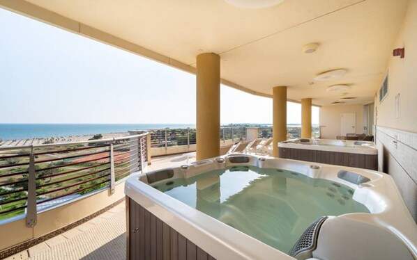 A rooftop terrace with a hot tub, a view of the sea, and a bar area.