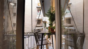 En balkon med et bord, stole og plantekasser.