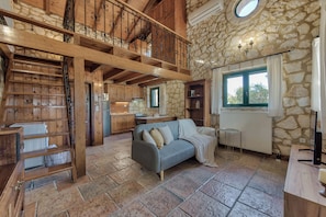 Cozy living area with a stone fireplace, wooden staircase, and large window.