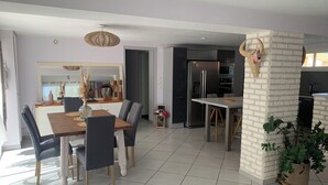A modern kitchen with a built-in refrigerator and microwave, a dining area with a wooden table and chairs, and a white brick accent wall. - Peace and comfort (Cessenon-sur-Orb)