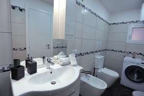 Features a large sink, compact toilet, and small vanity with mirror.