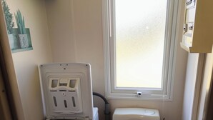 Ein kleines Badezimmer mit Toilette, Waschmaschine und einem Fenster für natürliches Licht.