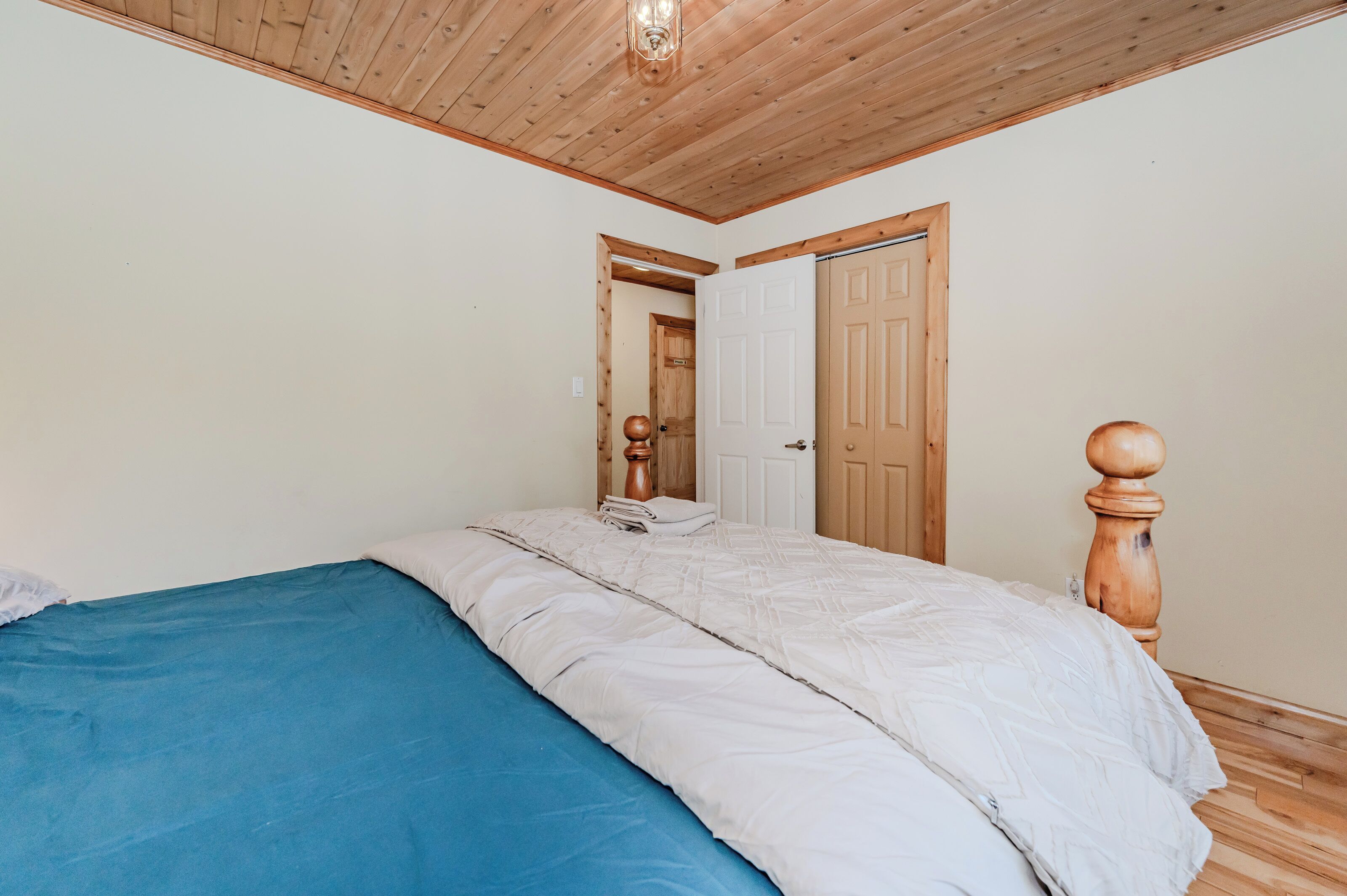 Een slaapkamer met een houten plafond, een bed met een blauwe matras en een wit hoofdeinde.