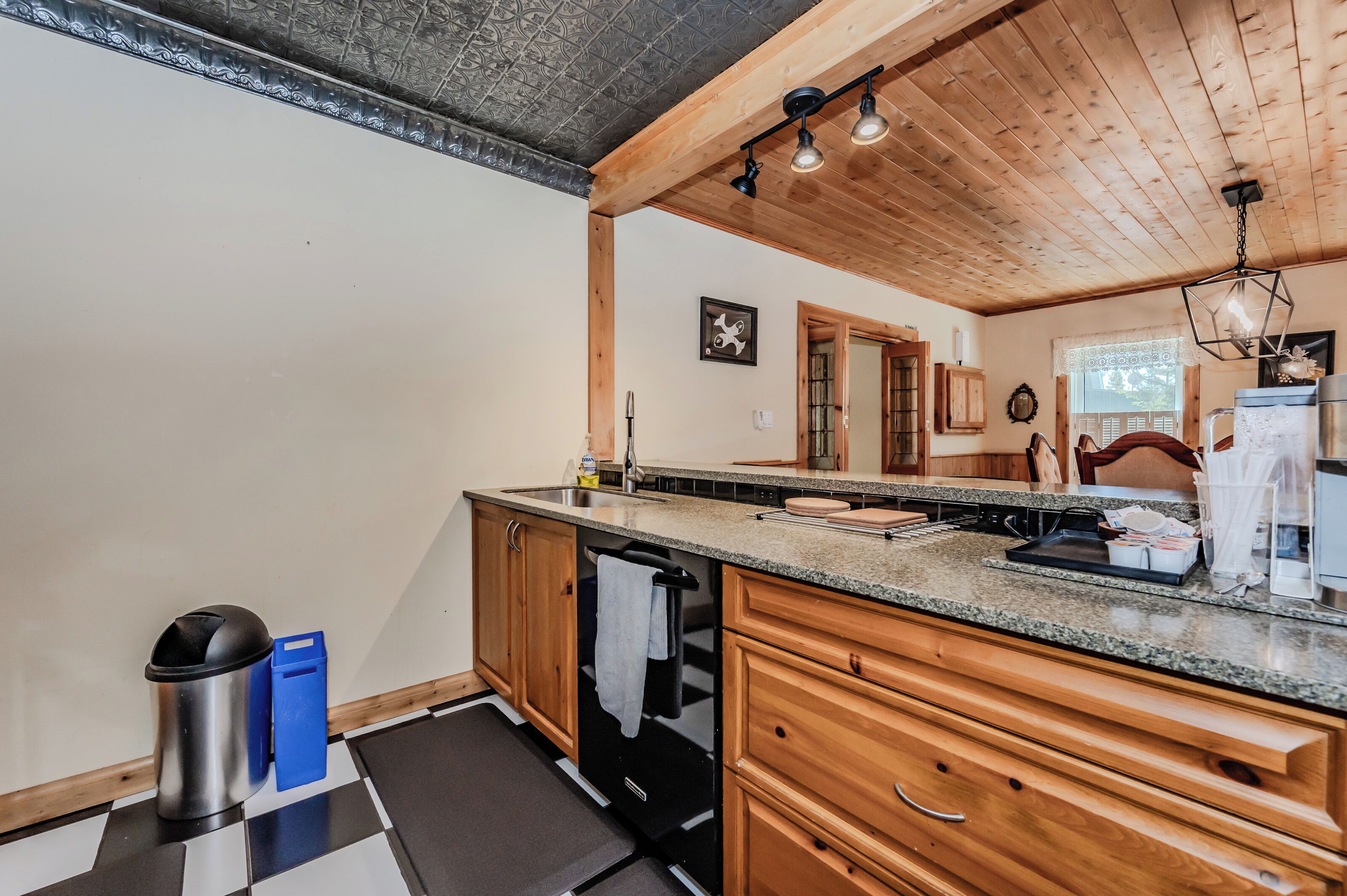 A kitchen with wooden cabinets, a granite countertop, a sink, and a dishwasher.