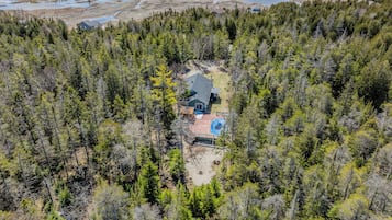 Vue aérienne d’une cabane entourée d’une forêt dense.