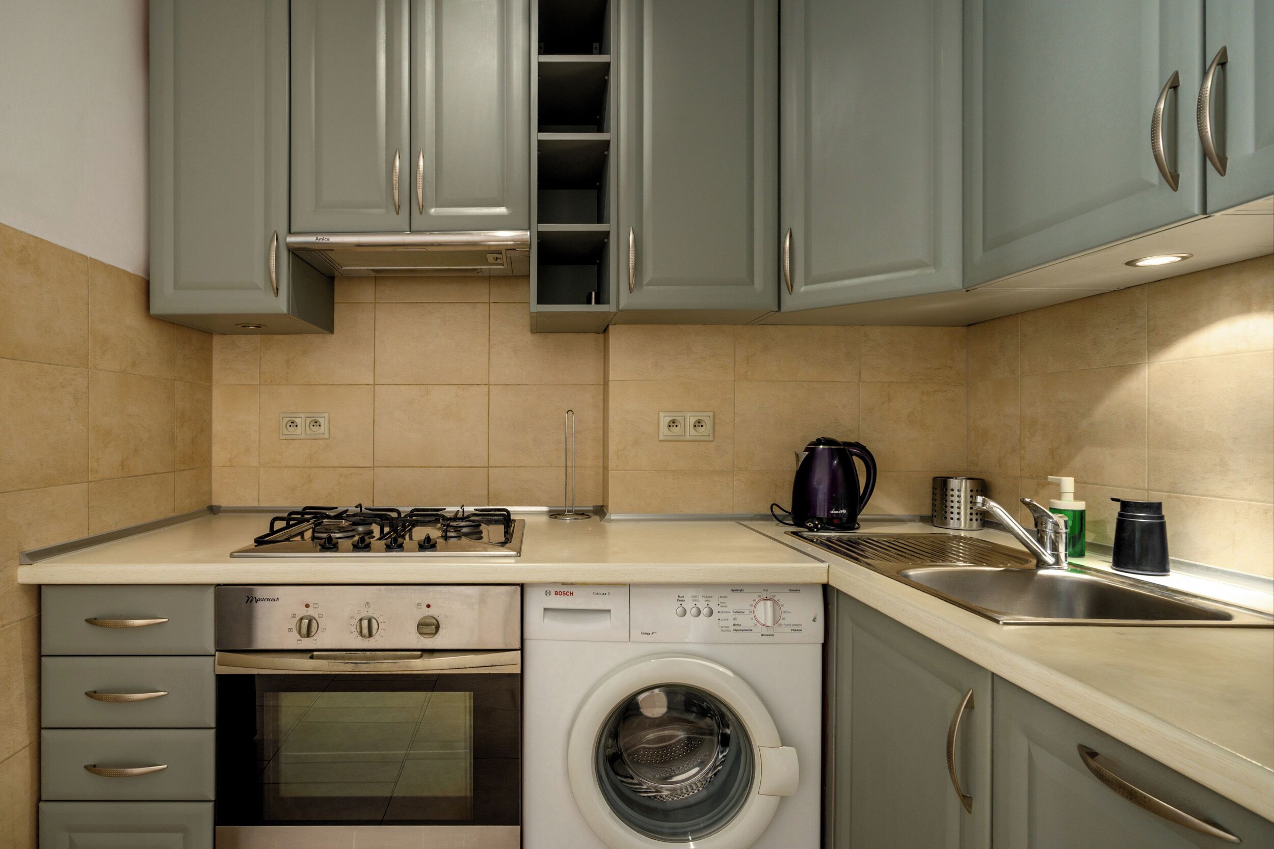 A compact kitchen with a gas stove, oven, and built-in washing machine.