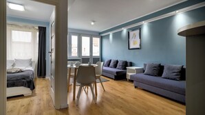 Una sala de estar moderna con un sofá, una mesa de comedor con sillas y una cama con vistas al exterior.