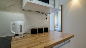 Una cocina con salpicadero de mármol, encimera de madera, cafetera y microondas sobre la encimera.