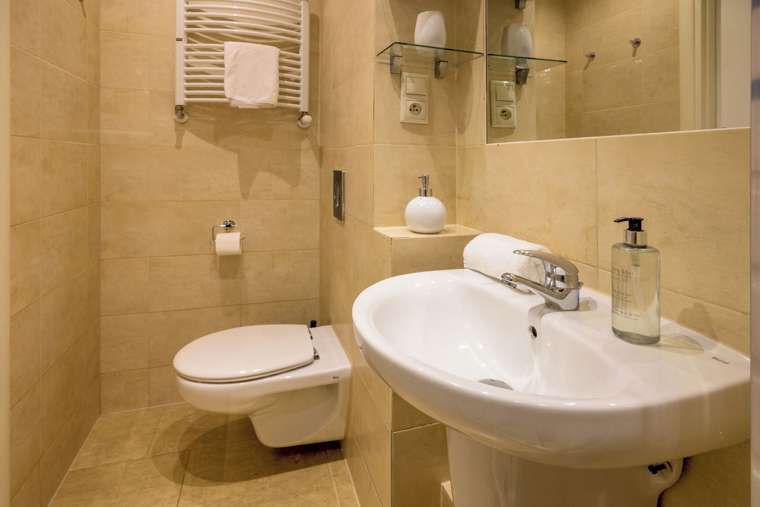 A modern bathroom with a toilet, sink, and glass shelf with toiletries.