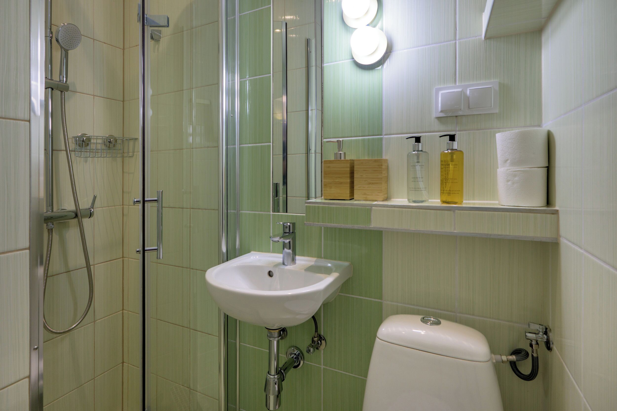 A bathroom with a glass shower enclosure, a white sink, and a toilet.