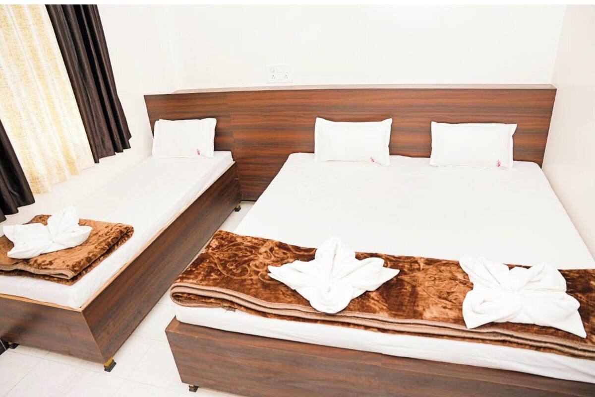 Habitación de hotel con dos camas, cada una con cabecero de madera, ropa de cama blanca y mantas marrones.