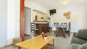 Un comedor con una mesa de madera, sillas y un televisor montado en la pared.